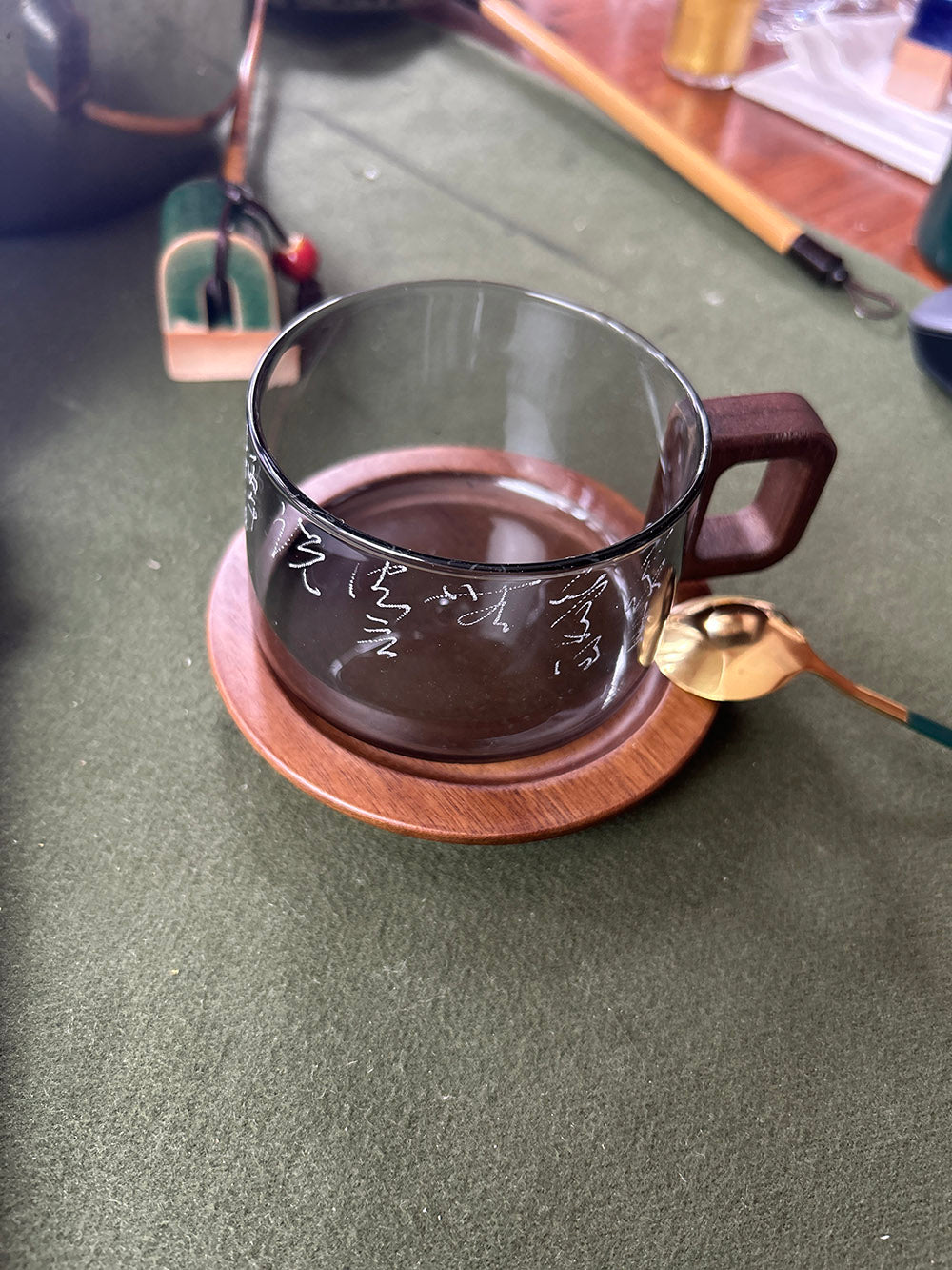 Smoky grey glass mug, full set view showing wooden handle, wooden coaster and hand‑engraved cursive Chinese calligraphy