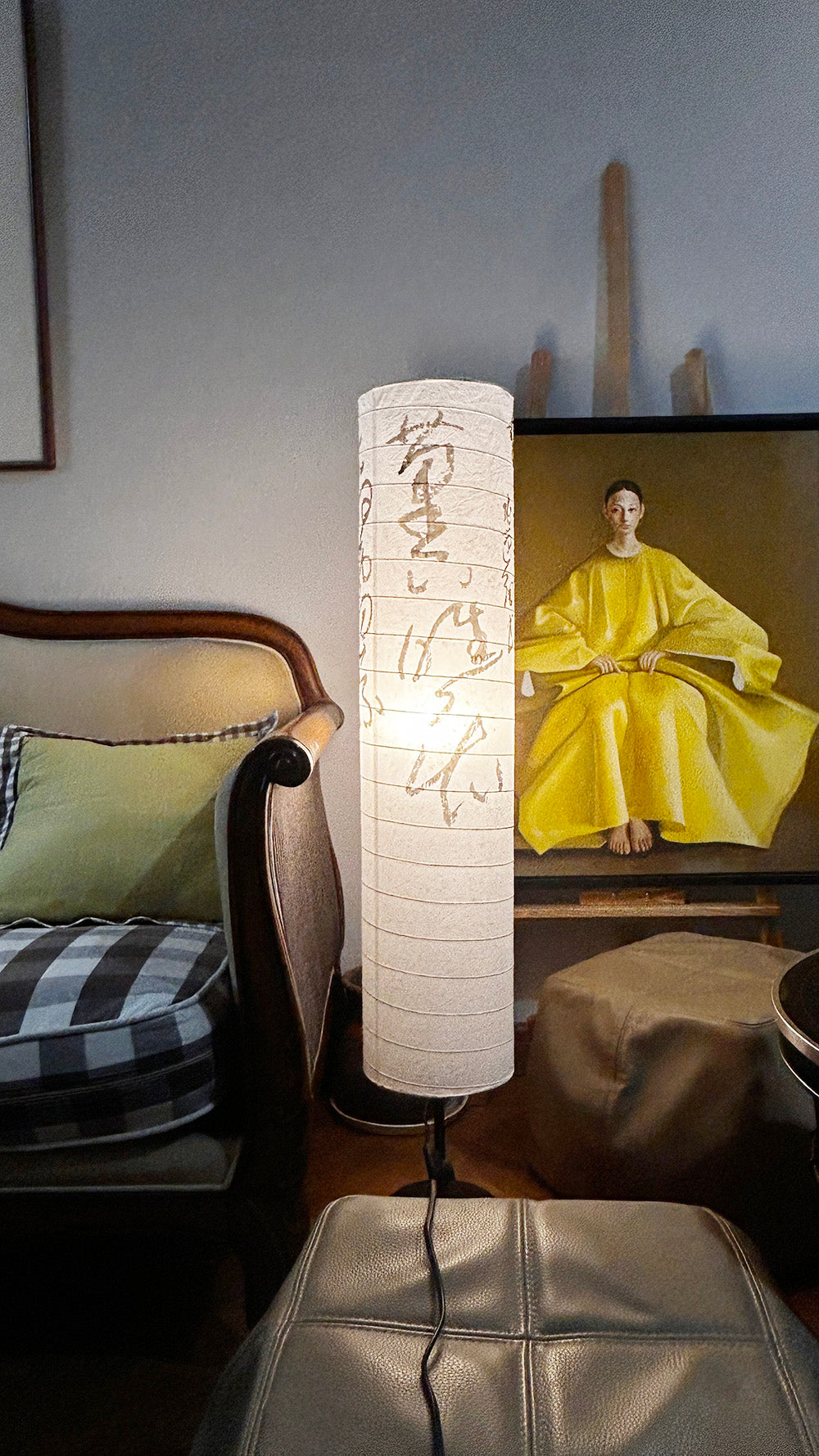 Side view of the tall cylindrical floor lamp next to a vintage sofa.