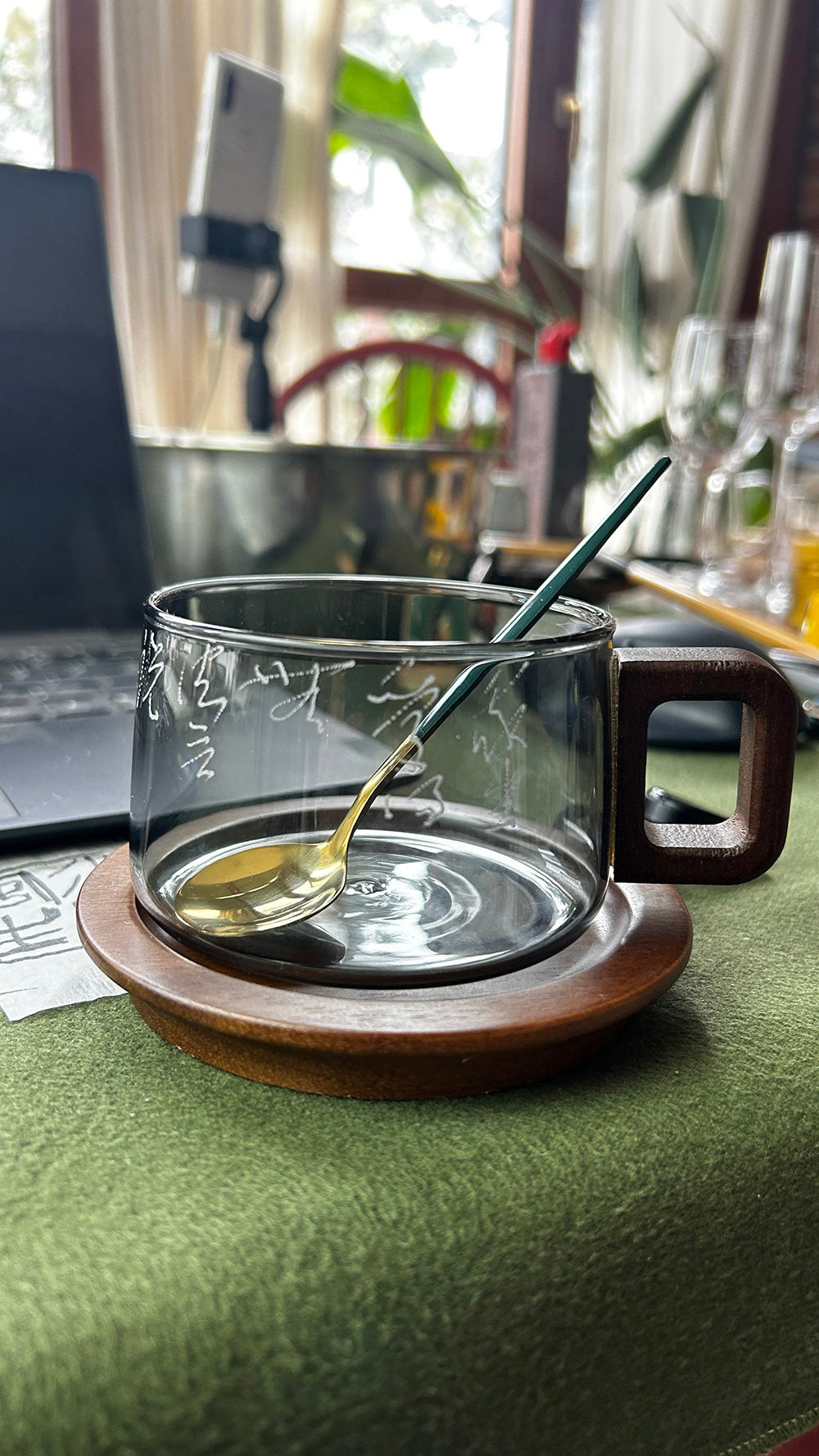 Detailed close‑up view of the mug with spoon, showing texture of smoky glass and hand‑engraved lettering