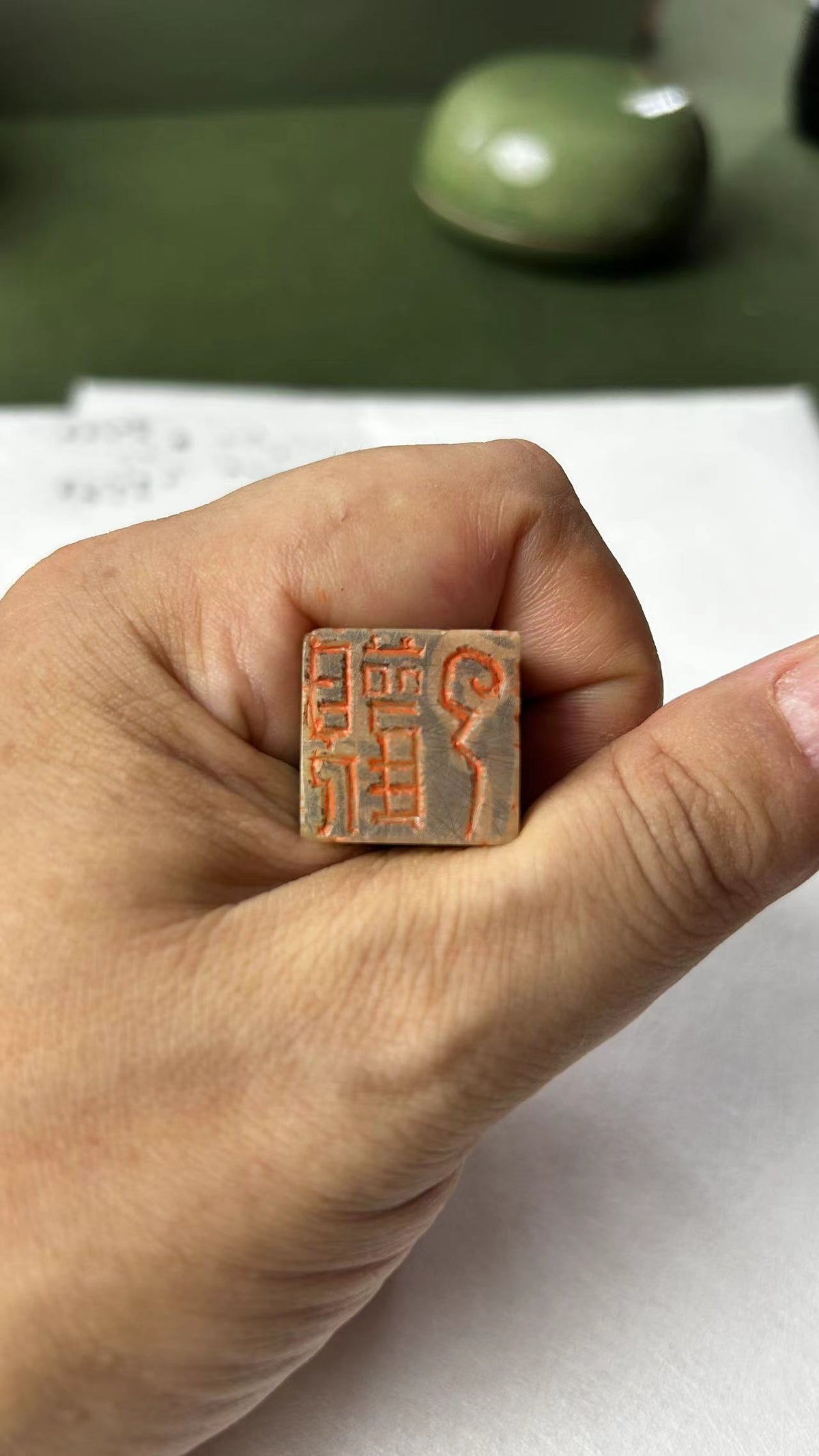 Close‑up of hand‑held Qingtian stone seal, carved stamp face