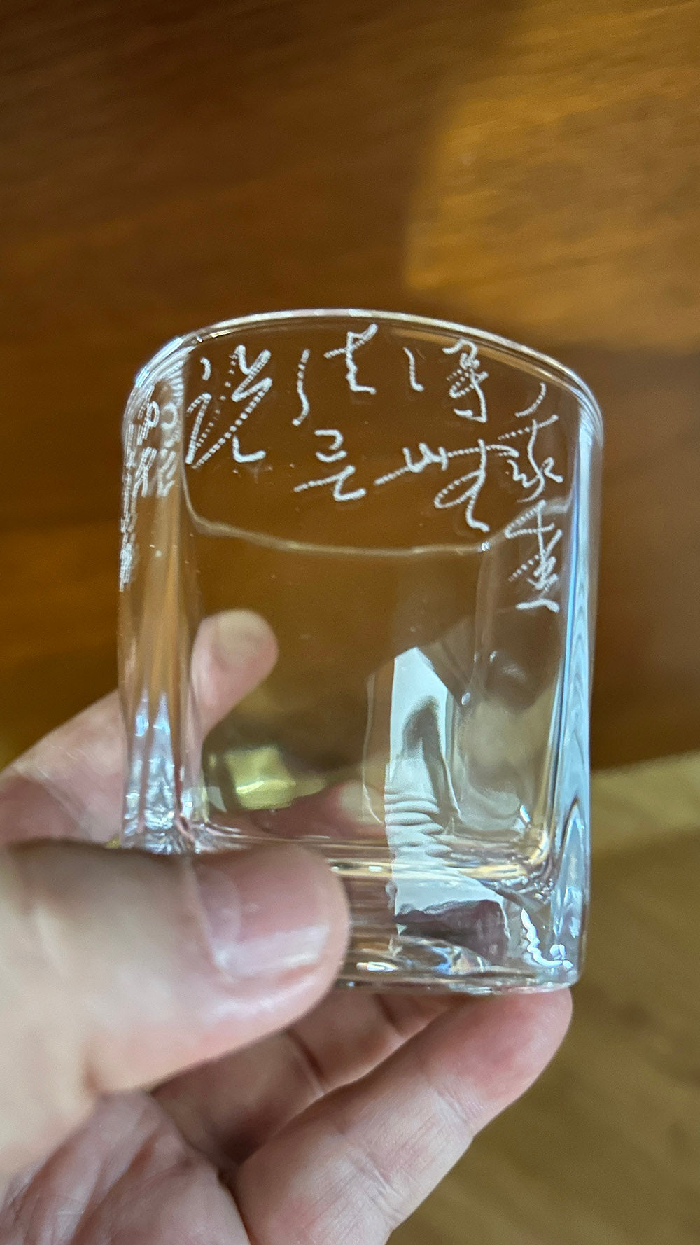 Detail shot of flowing hand‑carved frosted script on square drinking glass