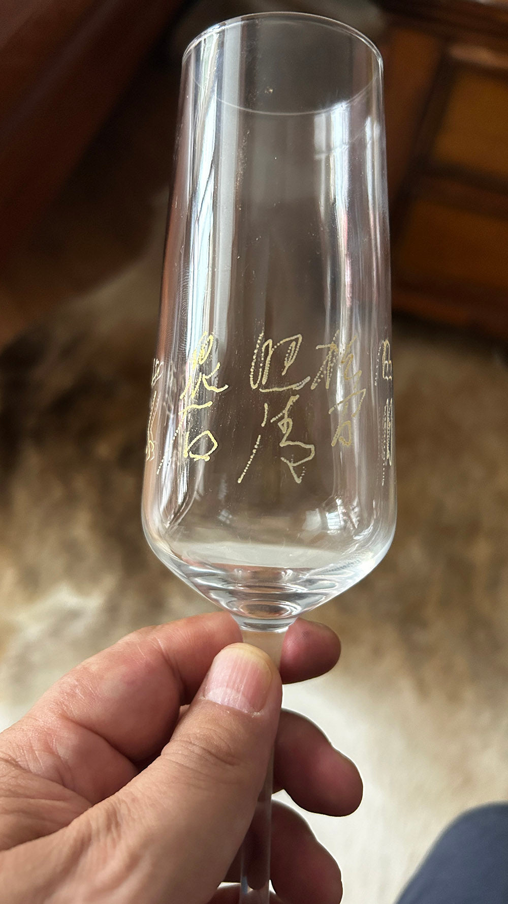 Close‑up shot of hand‑engraved cursive Chinese poem on clear crystal champagne flute, held in hand